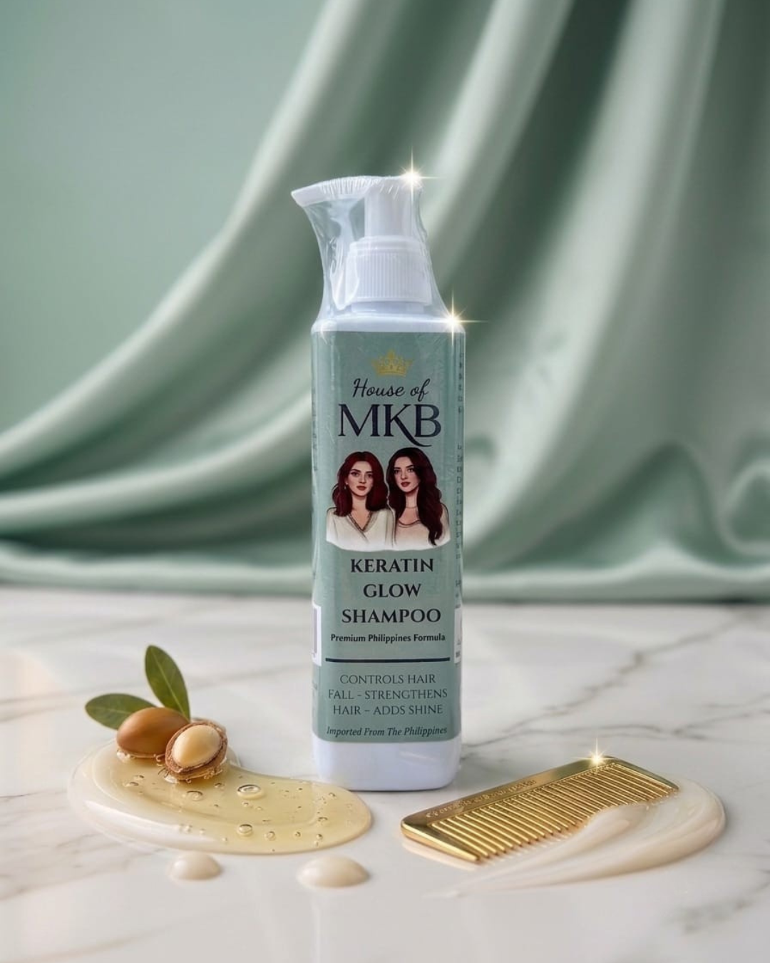 House of MKB Keratin Glow Shampoo bottle displayed on a luxury marble surface with green silk fabric background, gold comb, and raw argan oil ingredients.